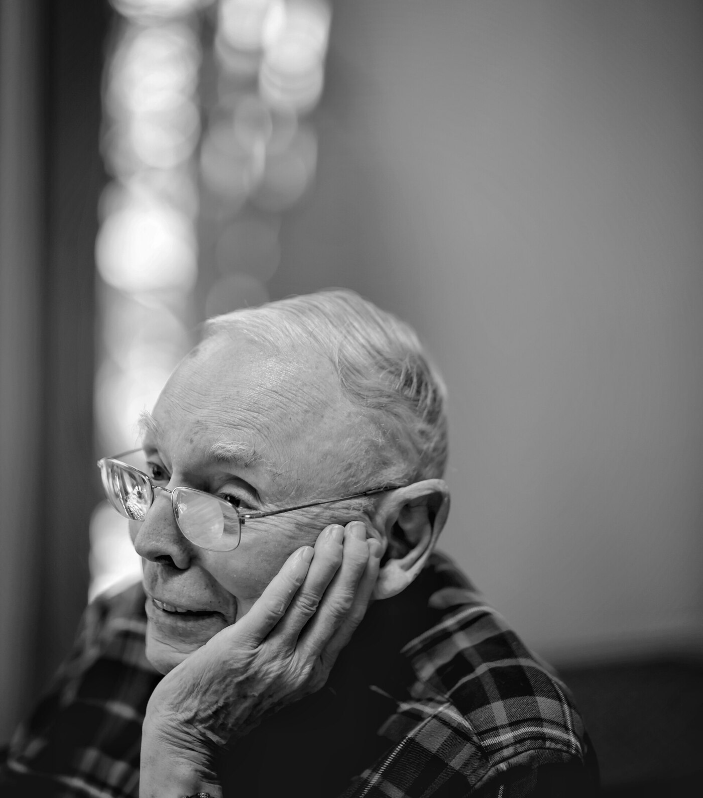 Charlie Munger at ninety-nine, at home in Los Angeles, chin resting on his hand, looking out of frame