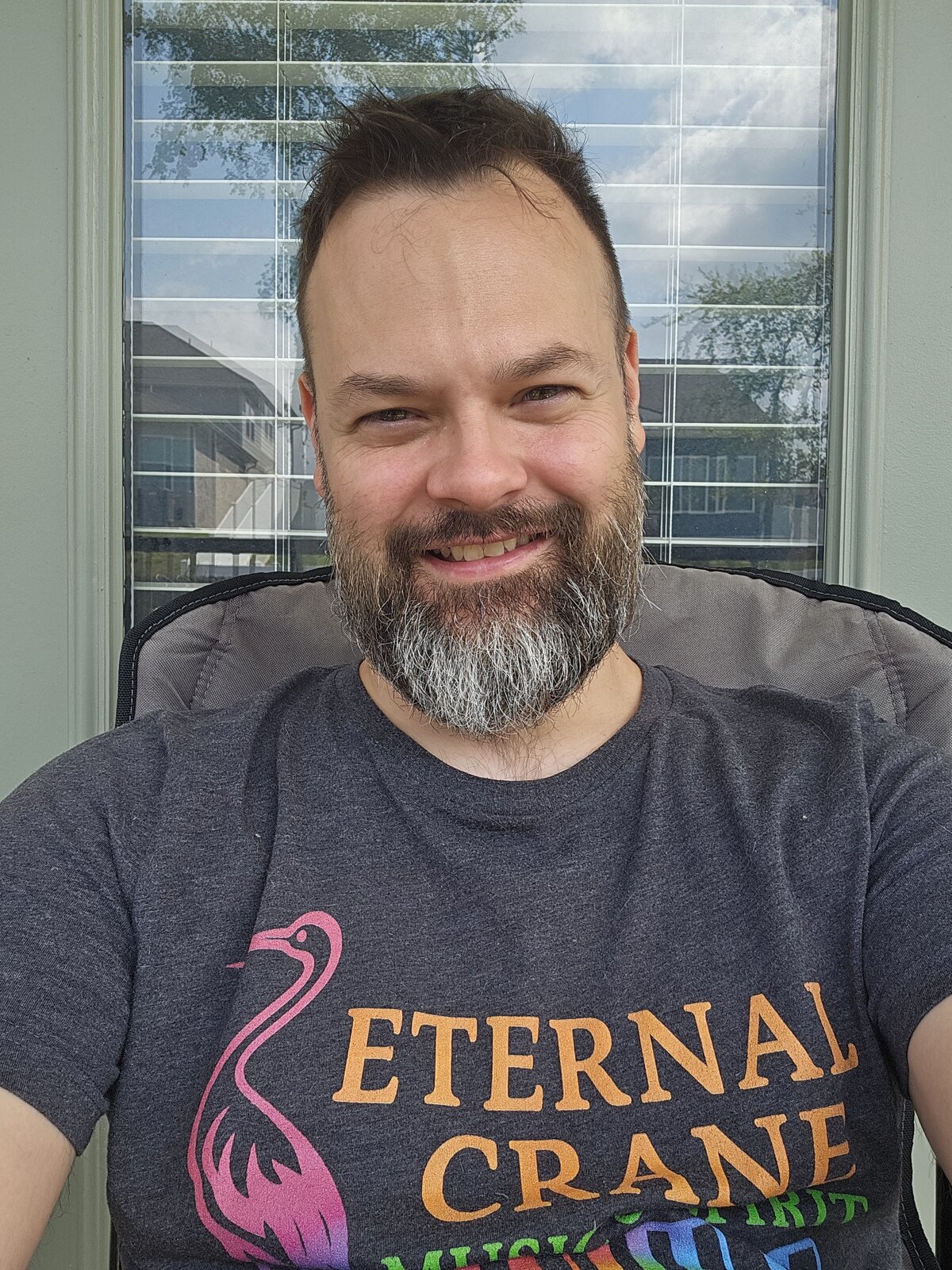 joEy, bearded and smiling, in a grey Eternal Crane T-shirt